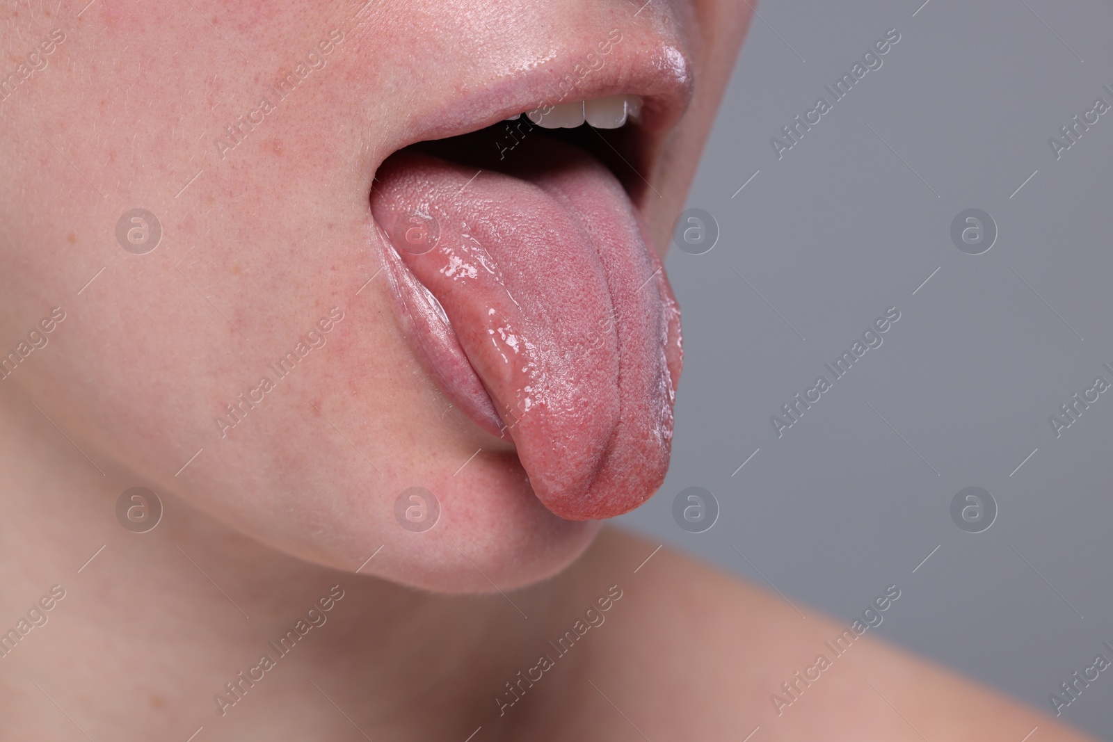 Photo of Woman showing her tongue on grey background, closeup. Space for text