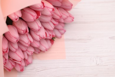 Photo of Bouquet of beautiful pink tulips on white wooden table, above view. Space for text