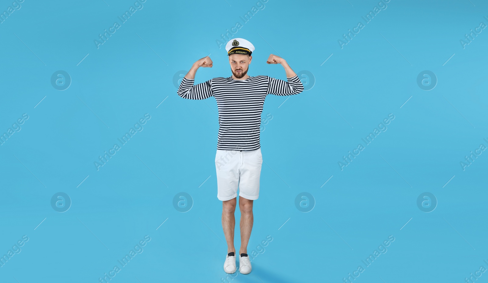 Photo of Strong sailor showing biceps on light blue background