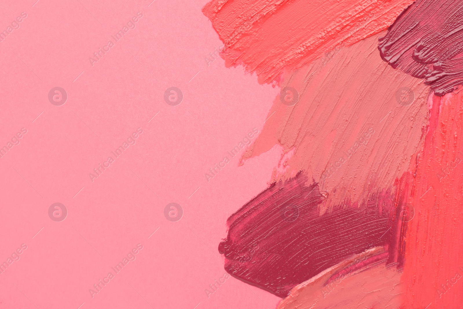 Photo of Smears of different beautiful lipsticks on pink background, top view. Space for text