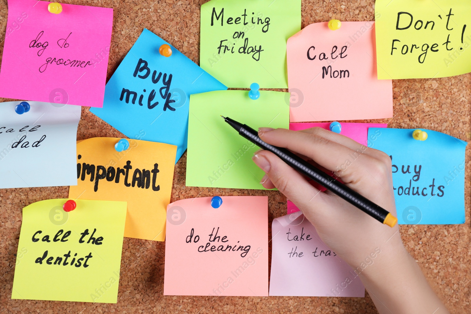 Photo of Woman writing paper note pinned to cork board, closeup