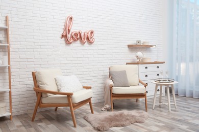 Photo of Cozy room interior with armchairs and balloon in shape of word Love. Valentine Day celebration