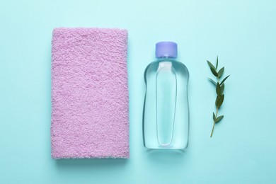 Photo of Bottlebaby oil, towel and leaves on turquoise background, flat lay