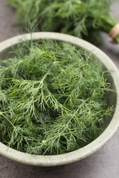 Photo of Bowl of fresh dill on grey table, closeup