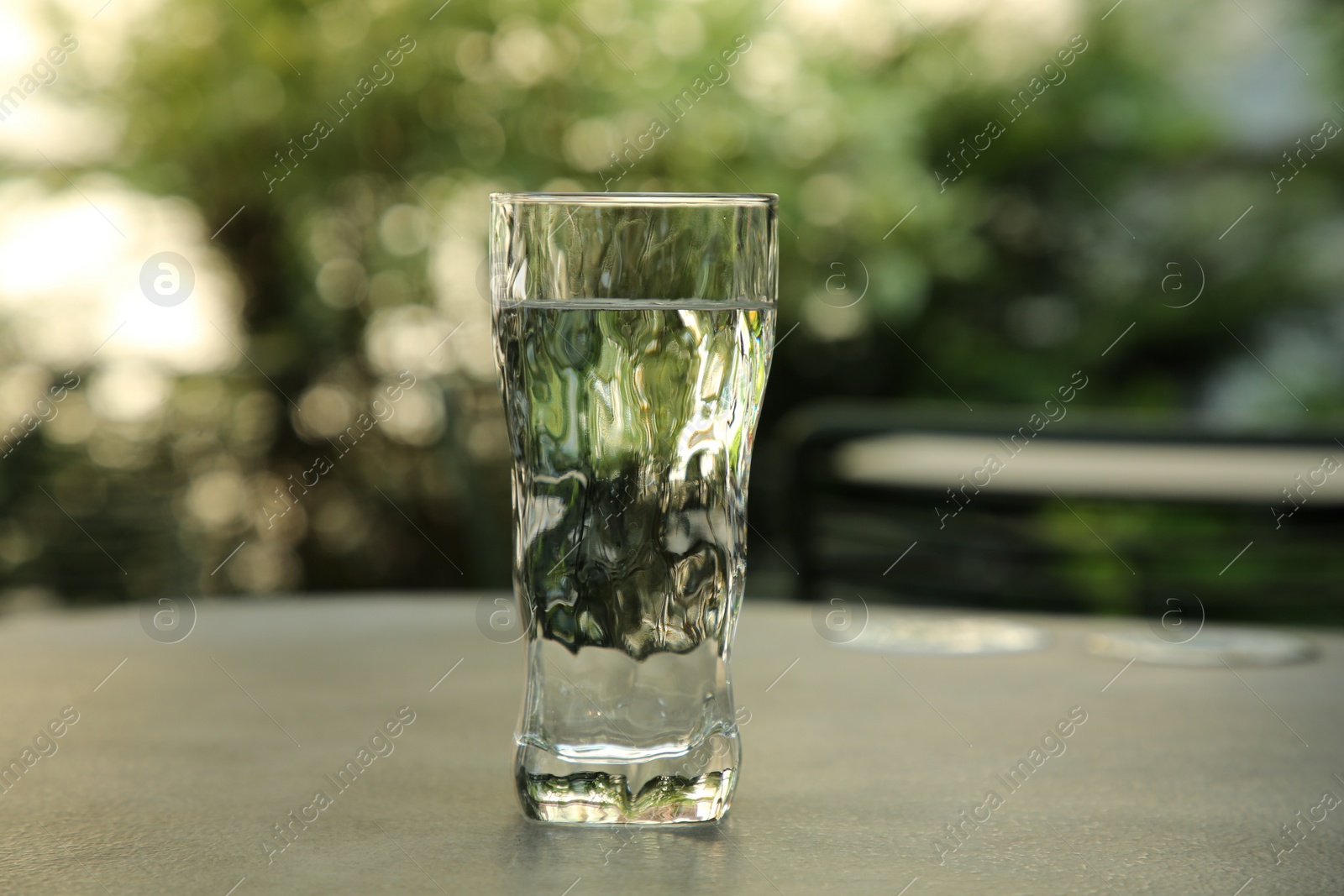 Photo of Glass of fresh water on grey table outdoors