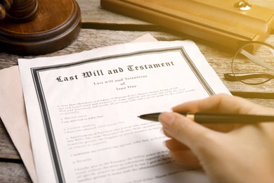 Image of Woman reading Last Will and Testament at wooden table, closeup