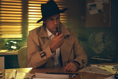 Old fashioned detective with smoking pipe at table in office