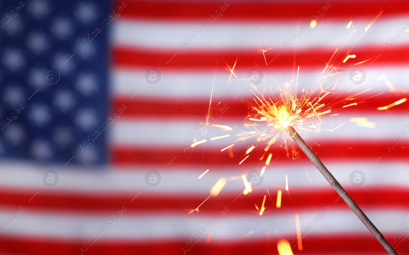 Photo of Burning sparkler against USA flag, closeup with space for text. Happy Independence Day