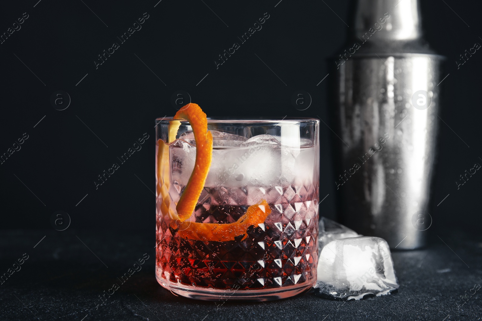 Photo of Glass of refreshing cocktail with ice cubes on dark background