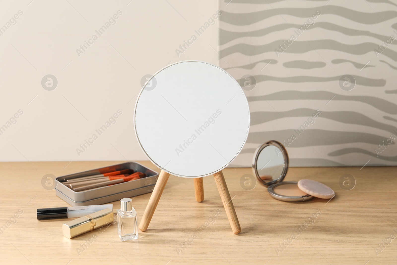 Photo of Mirror, makeup products and perfume on wooden dressing table in room