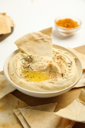 Photo of Delicious hummus with pita chips on wooden board, closeup