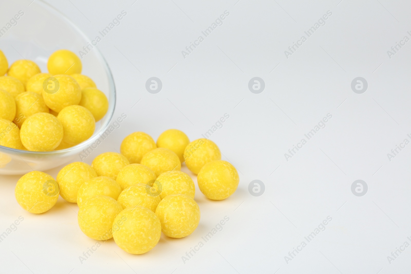 Photo of Tasty small lemon drops on white background