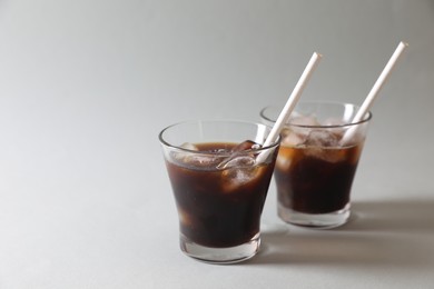 Photo of Refreshing iced coffee in glasses on grey background. Space for text