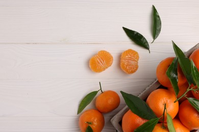 Photo of Delicious tangerines with leaves on white wooden table, flat lay. Space for text
