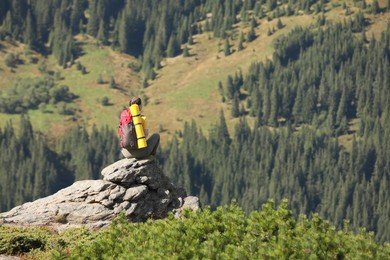 Photo of Tourist with backpack enjoying mountain landscape on rocky peak, back view