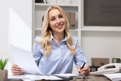 Secretary with document taking notes at table in office