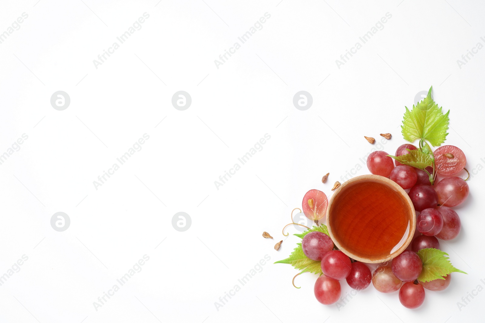 Photo of Composition with wooden bowl of natural grape seed oil on white background, top view. Organic cosmetic