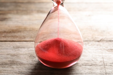 Photo of Hourglass with flowing sand on table, closeup. Time management