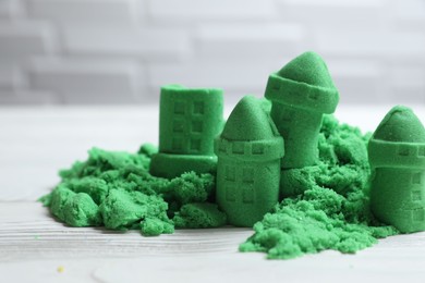 Castle figures made of green kinetic sand on white table, closeup