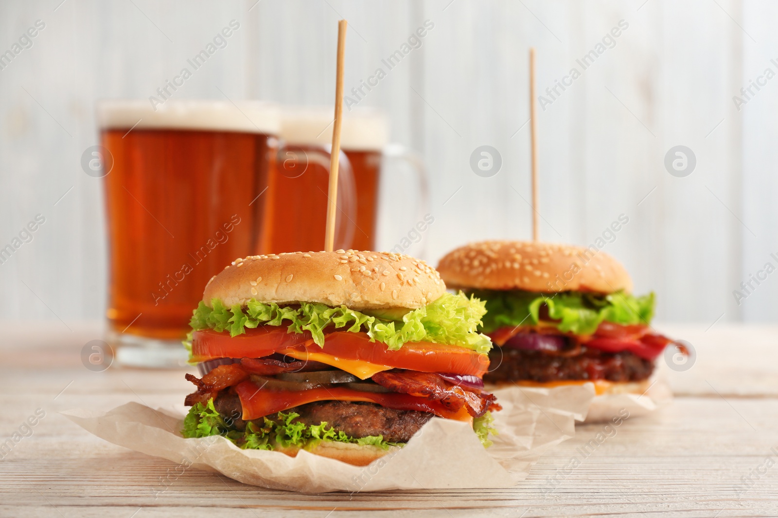 Photo of Tasty burgers with bacon on wooden table