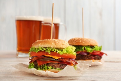 Photo of Tasty burgers with bacon on wooden table