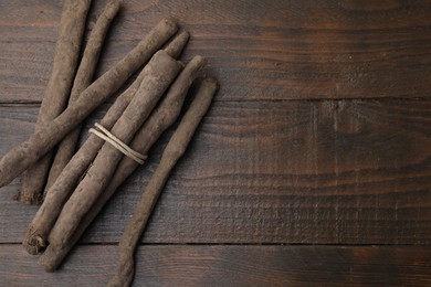 Photo of Raw salsify roots on wooden table, flat lay. Space for text