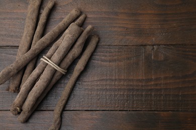 Raw salsify roots on wooden table, flat lay. Space for text