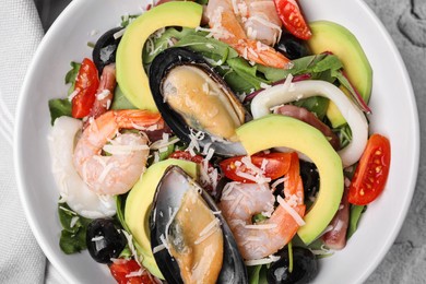 Photo of Bowl of delicious salad with seafood on white textured table, top view