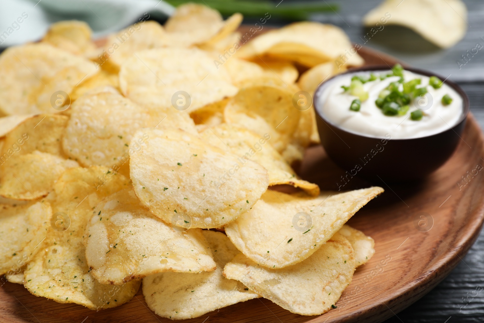 Photo of Chips with sour cream dressing on grey wooden table, closeup