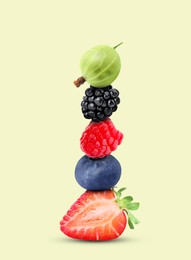 Stack of different fresh tasty berries on honeydew color background
