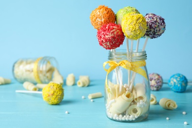 Photo of Yummy bright cake pops in glass jar full of sweets on table. Space for text