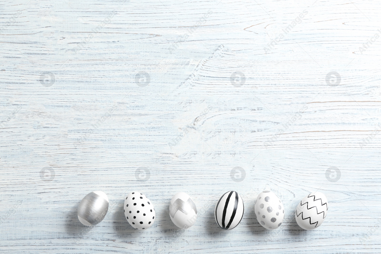 Photo of Painted Easter eggs on wooden background, flat lay with space for text