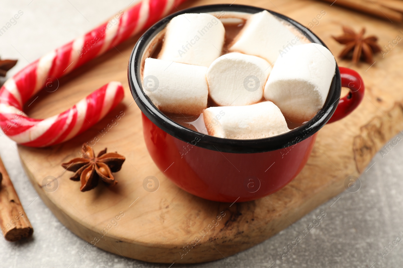 Photo of Tasty hot chocolate with marshmallows, candy cane and spices on light grey table, closeup