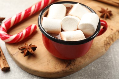 Tasty hot chocolate with marshmallows, candy cane and spices on light grey table, closeup