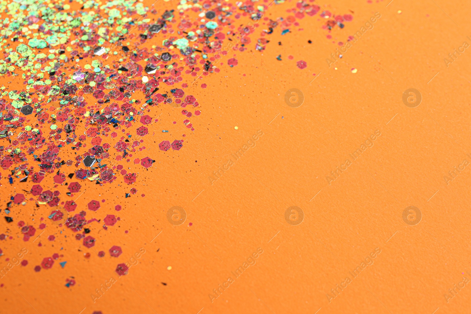 Photo of Shiny bright glitter on orange background. Space for text