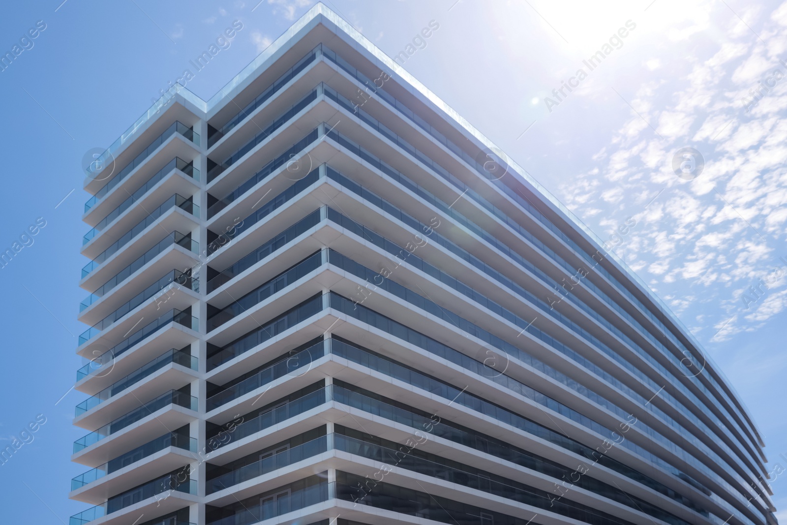 Photo of Exterior of residential building with balconies against blue sky, low angle view