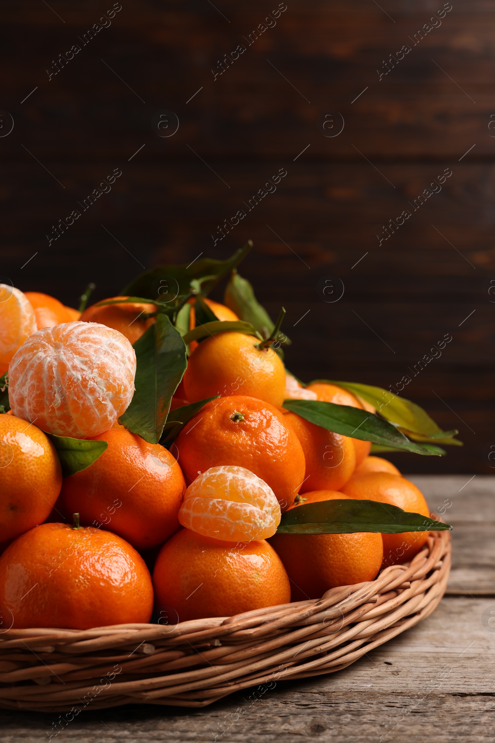 Photo of Fresh ripe juicy tangerines and green leaves on wooden table