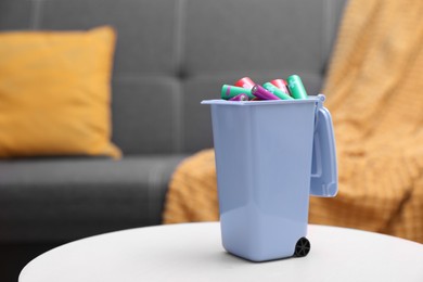 Mini recycling bin with different types of batteries on white table indoors. Space for text