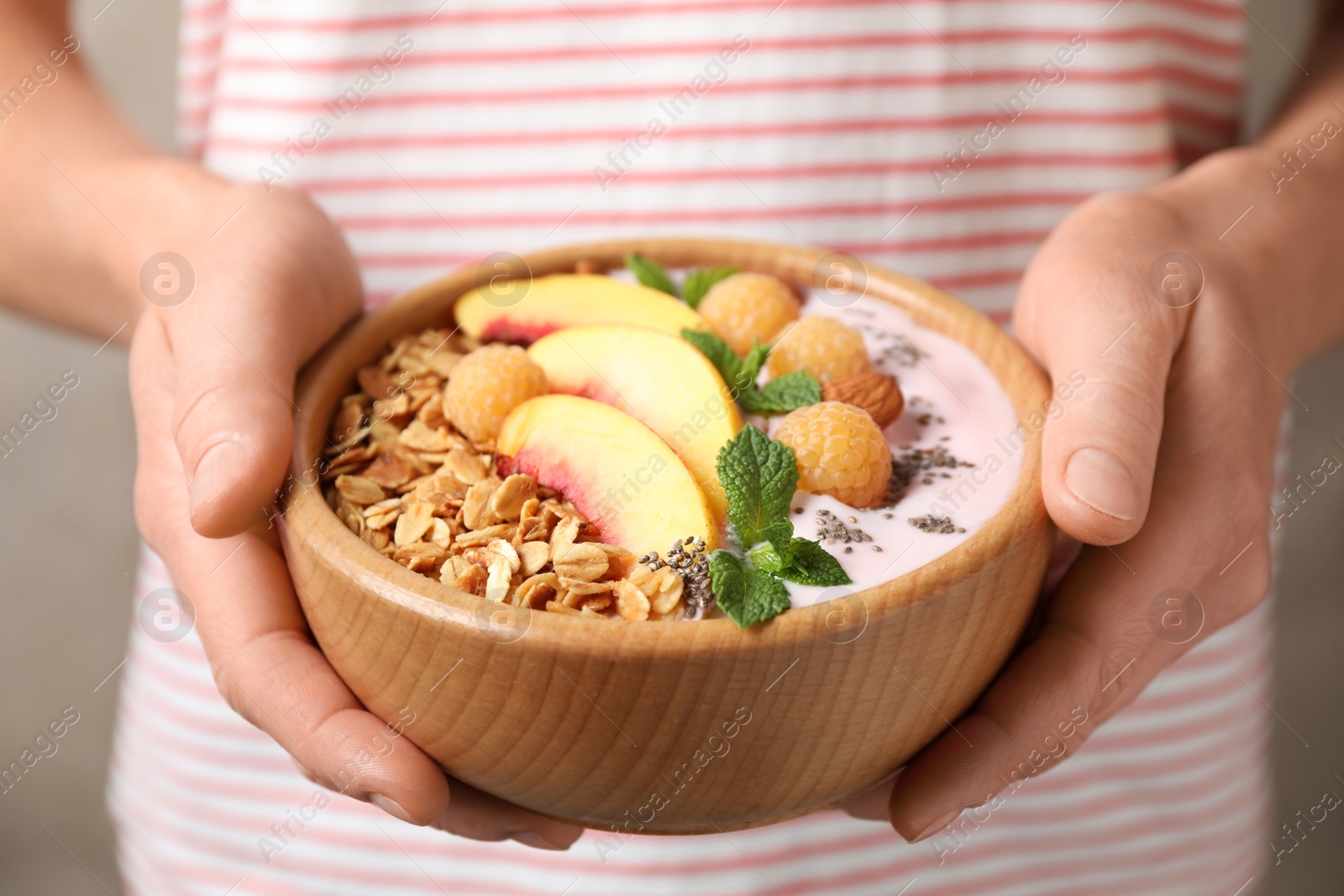 Photo of Woman holding bowl of tasty homemade granola with yogurt, closeup. Healthy breakfast