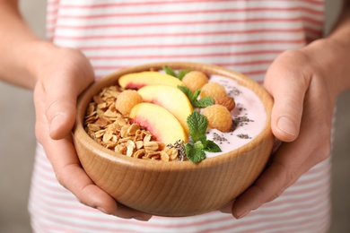 Photo of Woman holding bowl of tasty homemade granola with yogurt, closeup. Healthy breakfast