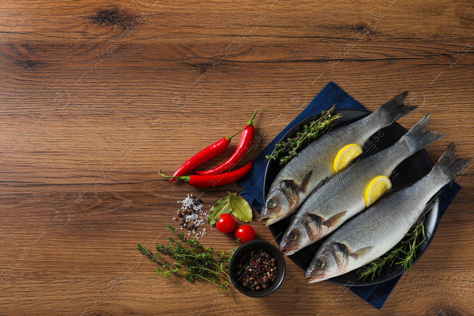 Photo of Tasty sea bass fish on wooden table, flat lay. Space for text