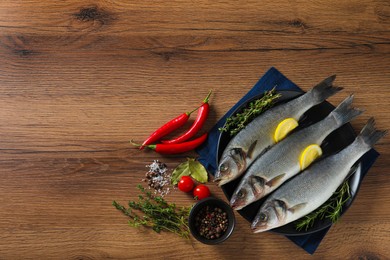 Photo of Tasty sea bass fish on wooden table, flat lay. Space for text