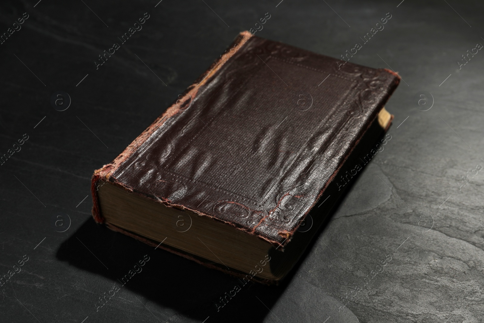 Photo of One old hardcover book on black textured table
