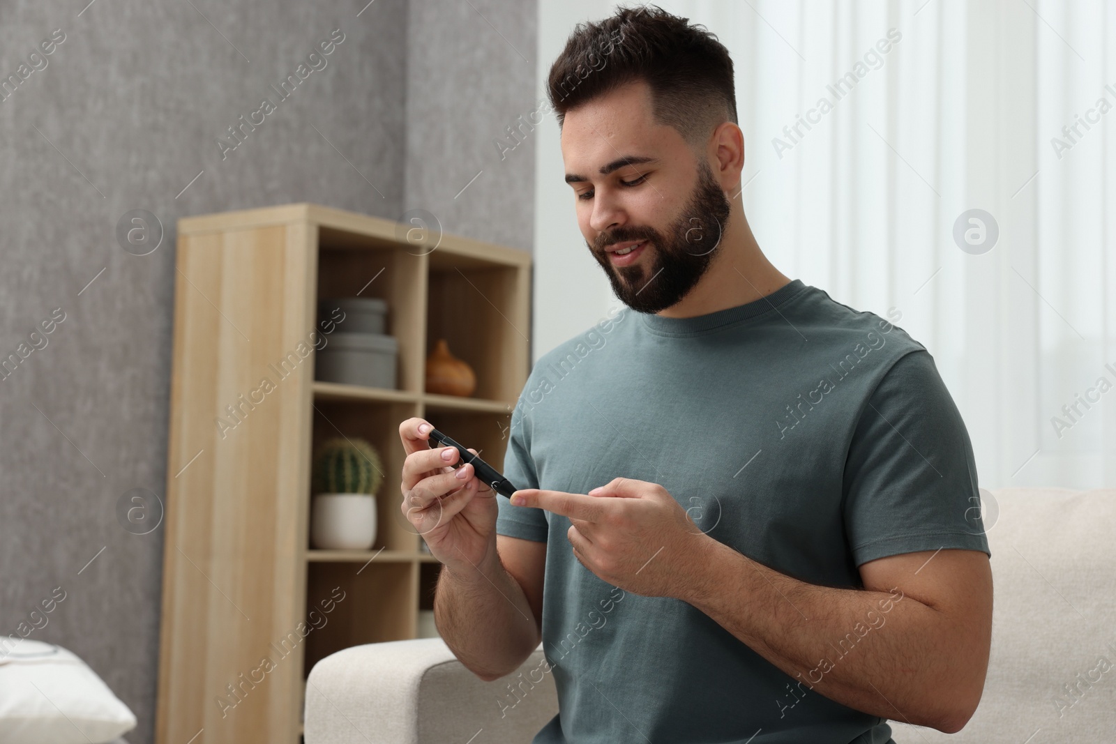 Photo of Diabetes test. Man checking blood sugar level with lancet pen at home