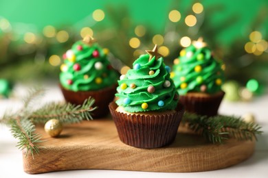 Photo of Tasty Christmas cupcakes on wooden board, closeup