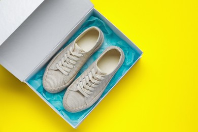 Comfortable shoes in cardboard box on yellow background, top view. Space for text
