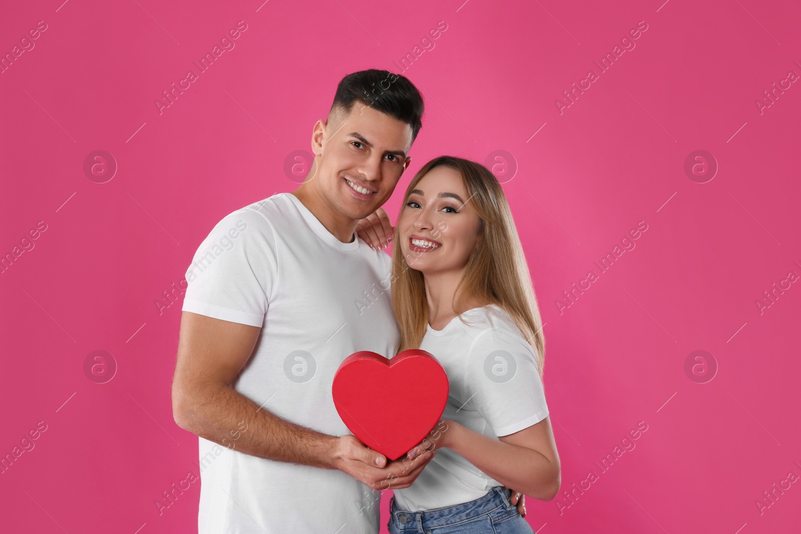 Photo of Lovely couple with decorative heart on pink background. Valentine's day celebration