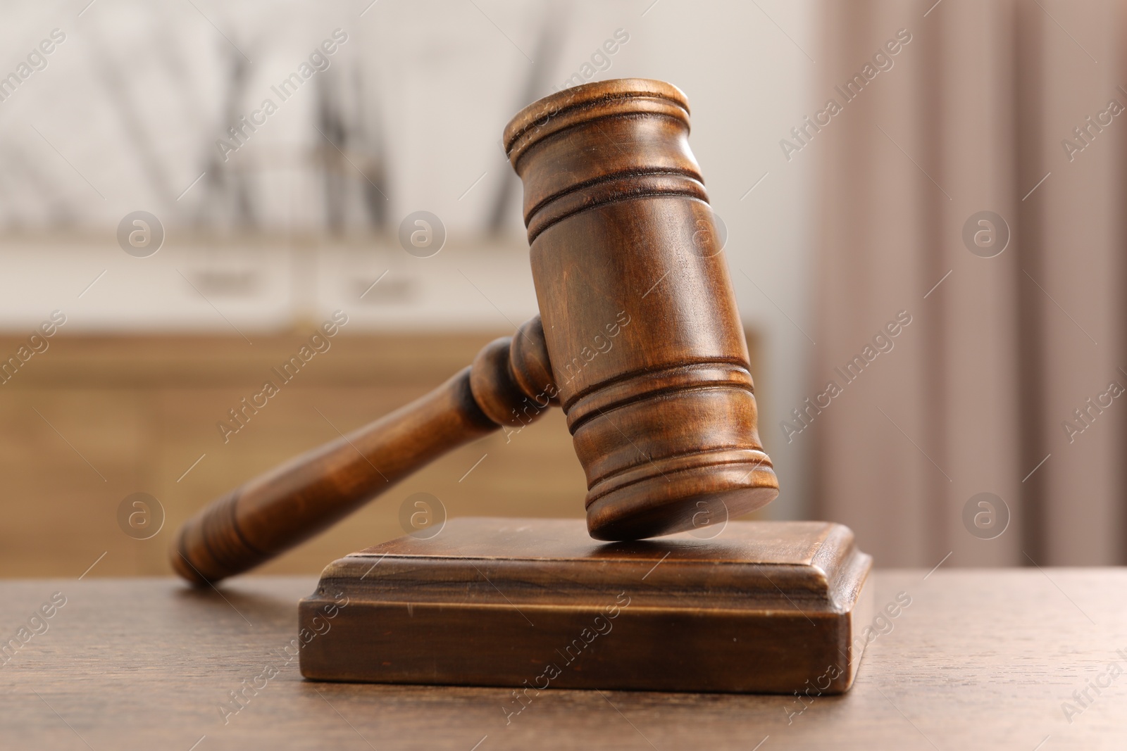 Photo of Wooden gavel and sound block on table indoors, closeup