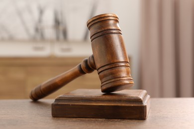 Photo of Wooden gavel and sound block on table indoors, closeup