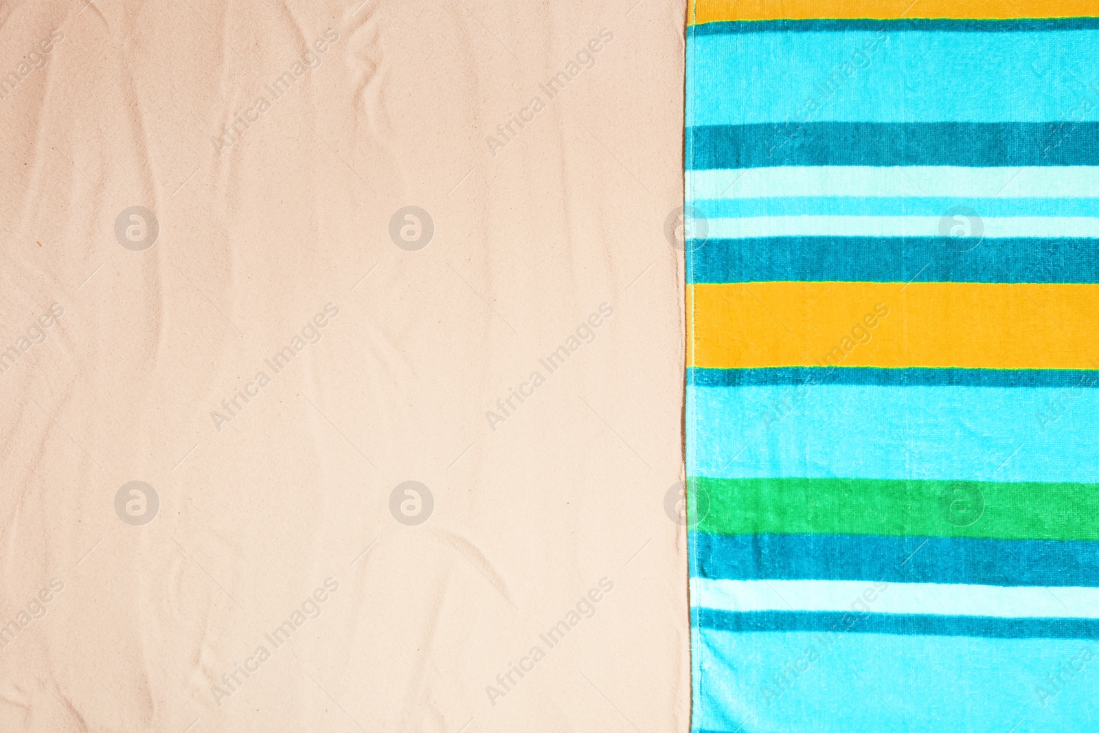 Photo of Bright towel on sand, top view with space for text. Beach object